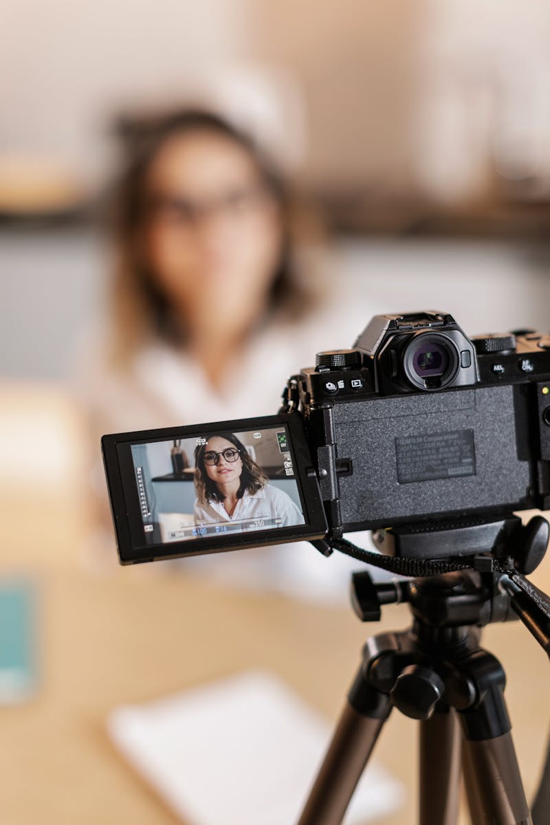 Woman recording video with DSLR camera, displaying on screen.